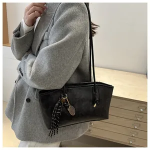 Dettaglio borsa tote nera in ecopelle con ciondolo a racchetta da tennis e nappa su fondo retrò