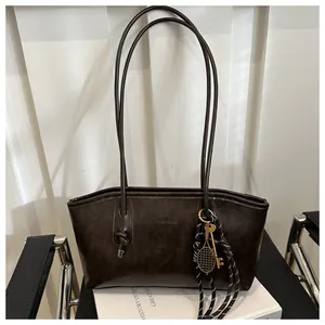 Dettaglio di borsa tote in pelle marrone vintage con charm a forma di racchetta da tennis