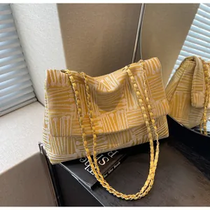Detailed top view of a yellow and white geometric pattern flap bag with a gold chain strap