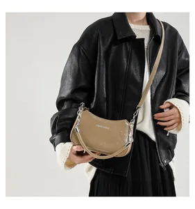 Detalle de bolso de media luna caqui con cadena metálica usado por una modelo