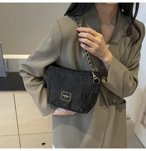 Détail du sac seau noir plissé avec bandoulière chaîne dorée et plaque logo