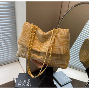 Detail of yellow and beige textured woven chain bag with abstract geometric lines