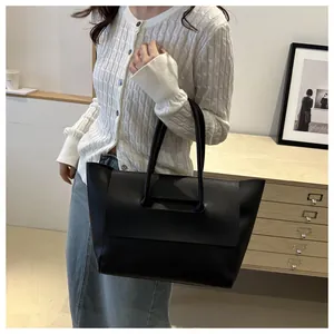 Minimalist matte black leather tote bag worn on shoulder for a chic commute style