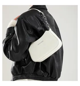 Detalle de bolso de media luna blanco para el brazo con cadena de plata y estampado