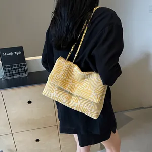 Large yellow and white woven shoulder bag with golden chain strap for summer commute