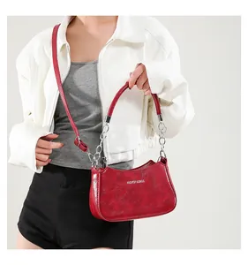 Detalle del bolso medialuna rojo con textura brillante, cadena plateada y bandolera