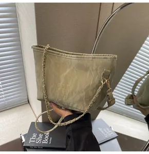 Détail du sac seau en cuir verni plissé vert clair avec bandoulière chaîne dorée