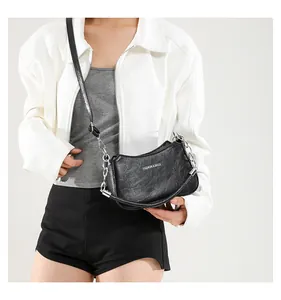 Detalle de bolso medialuna negro con cadena plateada y logotipo de texto de moda