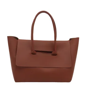 Minimalist terracotta brown leather tote bag with unique wide silhouette and top handles