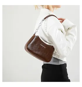 Detalle de bolso de media luna marrón vintage con textura de cuero y cadena de plata