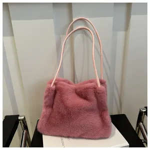 Detail der rosa Kunstpelz-Schultertasche mit Ledergriffen auf einem dekorativen Buch