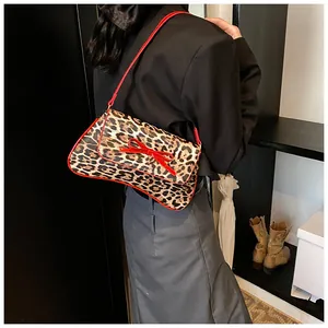 Detail view of leopard print crossbody bag with a red bow and shoulder strap