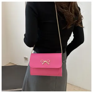 Detail van roze mini crossbodytas met gouden vlindergesp en elegante metalen ketting