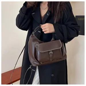 Détail du sac à bandoulière marron foncé avec surpiqûres blanches et poche à rabat