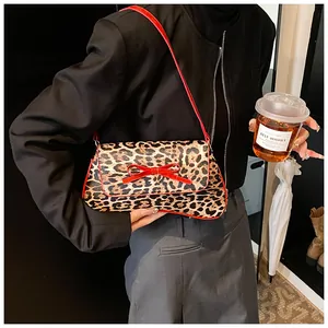 Close-up of leopard print shoulder bag with red bow detail on a black blazer