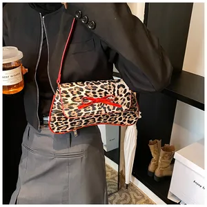 Detail of leopard print bag with red bow accent and matching leather strap in lifestyle setting