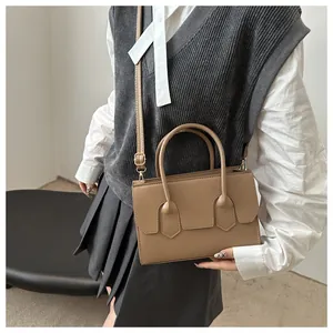 Fashionable khaki PU leather square bag shown on model with shoulder strap and handles