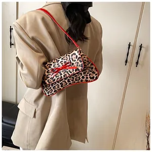 Leopard print underarm bag with red bow detail shown on model in khaki blazer