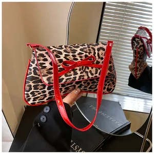 Close-up of leopard print shoulder bag with a red patent leather bow and shoulder strap