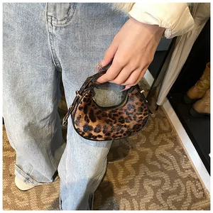 Detail der halbmondförmigen Tasche mit Leopardenmuster und goldener Schnalle im Alltag