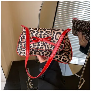 Close-up of leopard print handbag with red patent leather bow and reflective mirror effect