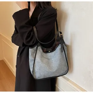 Détail du sac cabas en toile grise avec lanières en cuir noir et boucles dorées