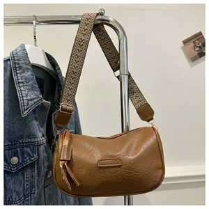 Detail einer braunen PU-Leder Umhängetasche mit FASHION-Patch und Webgurt
