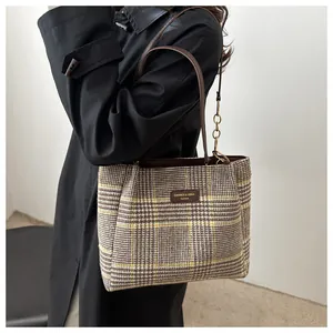 Seitenansicht der karierten Tragetasche aus Tweed kombiniert mit einem schwarzen Trenchcoat