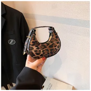 Makro-Detail der sichelförmigen Tasche mit Leopardenmuster, Goldreißverschluss und Schnalle