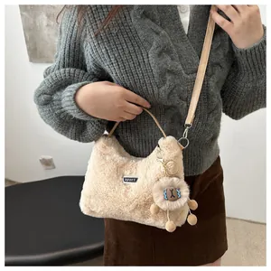 Detailansicht der beigen Kunstpelz-Handtasche mit Metallelement und Löwenanhänger