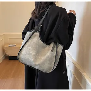 Gros plan d'un grand sac cabas gris avec bandoulière noire porté par un mannequin