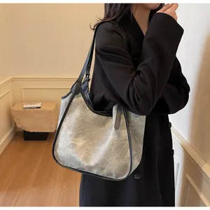 Sac hobo en tissu mat gris avec bordure noire porté par un mannequin femme