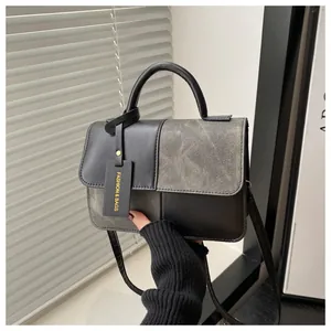 Detail der grau-schwarzen Lederhandtasche mit Farblock-Design und rundem Metallgriff