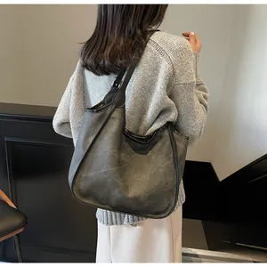 Détail macro du cabas gris foncé montrant le cuir PU texturé vintage et la bandoulière