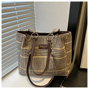 Detail der Tweed-Tasche mit Hahnentrittmuster und Goldkette auf Holzoberfläche