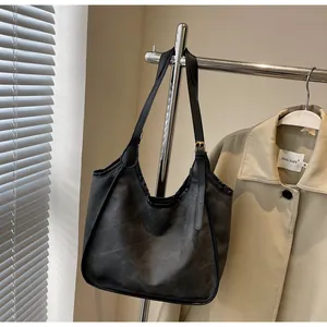 Détail d'un grand cabas noir vintage avec boucle métallique réglable sur un cintre
