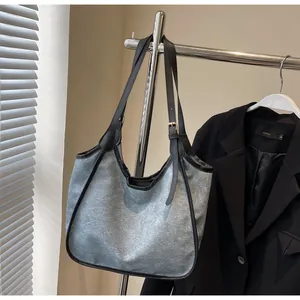 Détail d'une sangle ajustable avec boucle dorée sur un grand sac cabas en toile