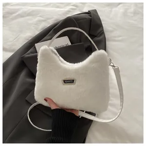 Detailansicht der weißen Webpelz-Handtasche mit silberner Sport-Metallplakette