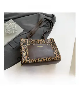 Detail of leopard print tote bag with brown leather pocket and dual shoulder straps