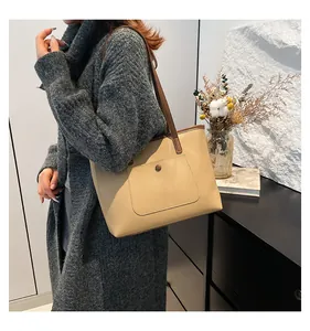 Sac fourre-tout beige avec poche à boucle ronde et bandoulières marron sur manteau