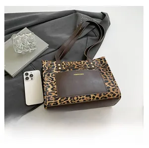 Detail of leopard print tote bag with brown leather trim and front pocket