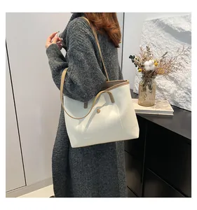 Modèle portant un grand sac cabas crème avec bordure kaki pour un style décontracté
