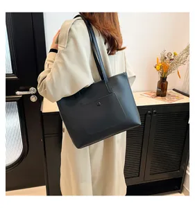 Détail d'un grand sac cabas noir avec une poche avant fonctionnelle et un bouton-pression