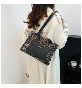 Detail of trendy leopard print tote bag with black leather strap and gold rivet accents