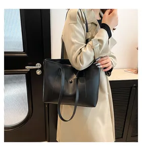 Détail d'un sac cabas en cuir noir avec poche avant à pression et fines bandoulières