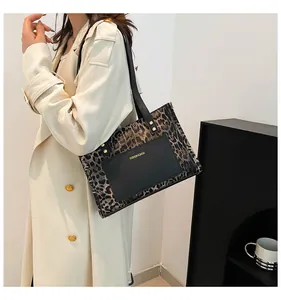 Detail of leopard print tote bag with black leather front pocket and gold logo