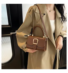 Borsa a tracolla marrone con fibbia dorata abbinata a un trench kaki alla moda