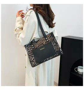 Close-up of leopard print tote bag with black pocket and dual straps worn by a model
