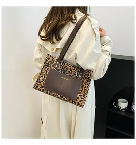 Detailed side view of a leopard print tote bag with brown leather strap worn by a model