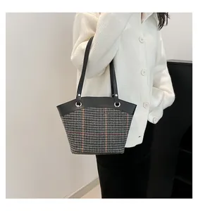 Détail du motif à carreaux classique et de la bandoulière en cuir noir du sac seau